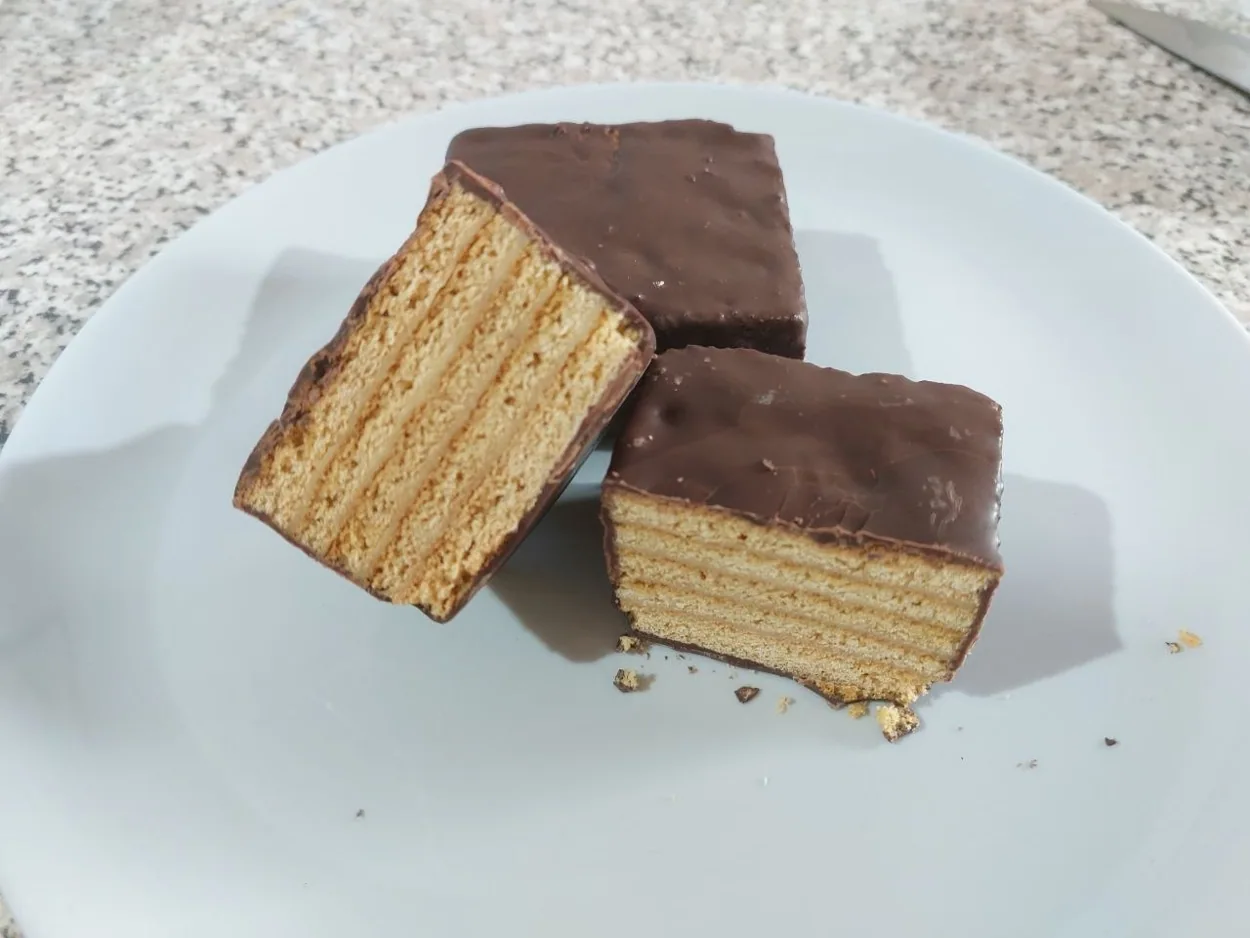 Medovik real KA’A LUXE, bañado en chocolate, cortado para mostrar sus capas de miel y crema